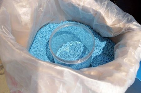 Foto de Un frasco de vidrio en una bolsa de pellets de plástico azul claro para producir un disco fonógrafo. - Imagen libre de derechos