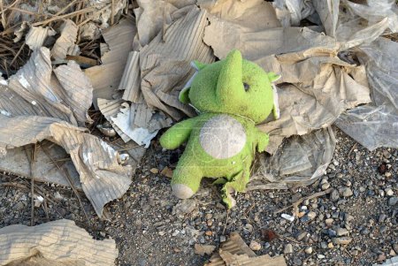 Photo for A green teddy bear left in a pile of garbage area, environment concepts. - Royalty Free Image