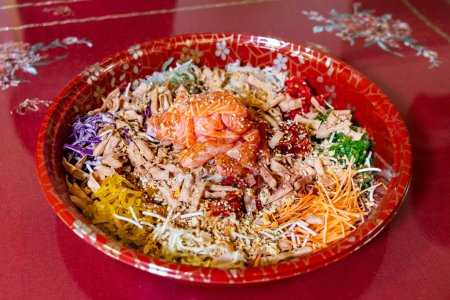 Photo for Serving of yusheng or yee sang with raw salmon on red background during Chinese New Year believed to bring good luck and prosperity - Royalty Free Image