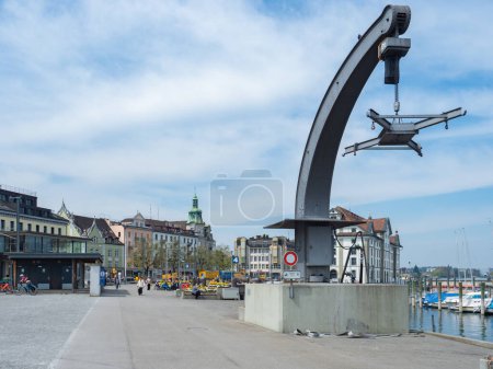 Photo for The city of Rorschach, Switzerland is directly situated at lake Constance. Situation of harbour crane on the big concrete plaza in front of the historic buildings of the old town. - Royalty Free Image