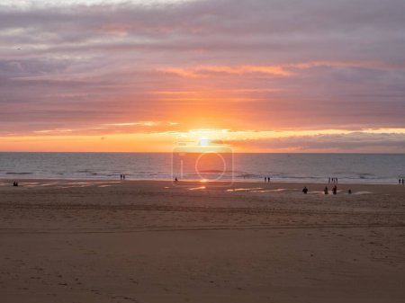 Una tarde soleada en la playa de la ciudad de Oostende, Bélgica. Gente observando la puesta de sol en la costa del Mar del Norte.