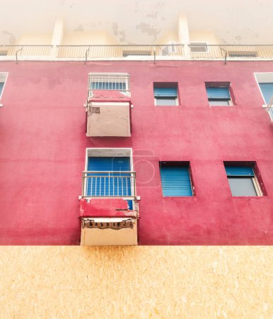 Téléchargez les photos : Façade rouge du vieux bâtiment abandonné, fenêtre et balcons - en image libre de droit