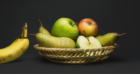Téléchargez les photos : Nature morte avec panier de fruits, poires, pommes et bananes isolées sur gris - en image libre de droit