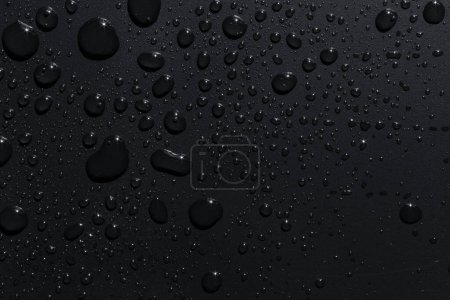 Foto de Primer plano de las gotas de lluvia negras sobre una superficie oscura, fondo abstracto - Imagen libre de derechos