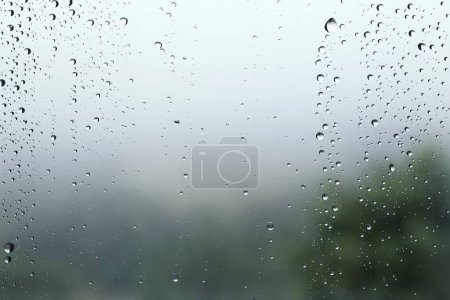 Téléchargez les photos : Gouttes de pluie sur le verre, paysage flou sur le fond - en image libre de droit