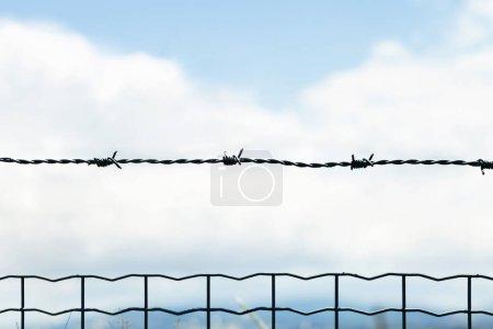Foto de Valla con alambre de púas, cielo azul sobre fondo - Imagen libre de derechos