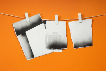 Foto de Cartas viejas desgarradas colgadas con pinzas de ropa, fondo naranja - Imagen libre de derechos
