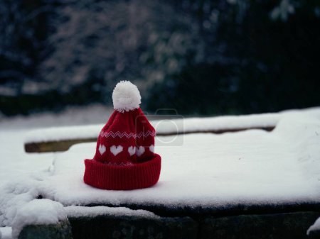 Red knitted winter hat in the snow wide shot selective focus