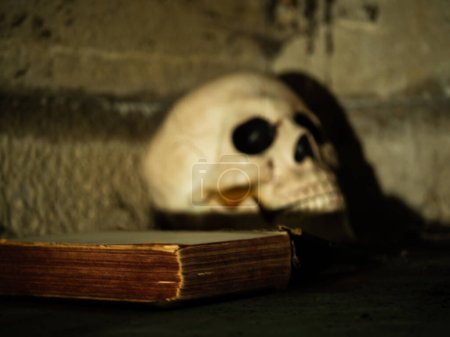 Téléchargez les photos : Ancien livre usé effrayant avec le crâne humain foyer sélectif tir moyen - en image libre de droit