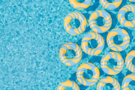 Foto de Representación 3D de múltiples anillos inflables de rayas amarillas y azules flotando en el agua azul clara de una piscina. Concepto de ocio y verano. - Imagen libre de derechos