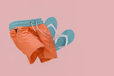 Stylish orange swim shorts paired with turquoise flip flops, elegantly displayed against an isolated pink background. Beachwear fashion concept. 3d rendering