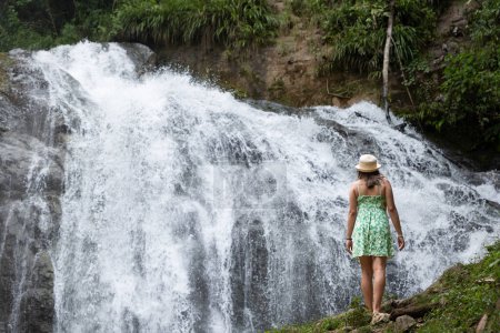 Woman traveler contemplates a waterfall in the Peruvian jungle.