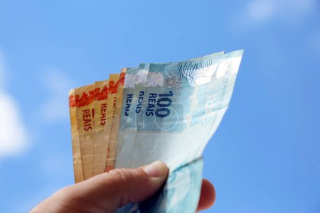 Foto de Billetes reales brasileños con el cielo azul en el fondo - varios cientos de billetes - Imagen libre de derechos