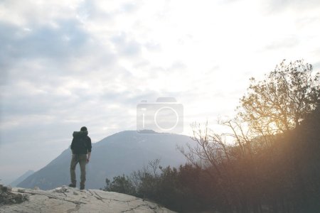 Téléchargez les photos : Randonneur se reposant en respirant dans la nature en observant le coucher du soleil sur les montagnes - en image libre de droit