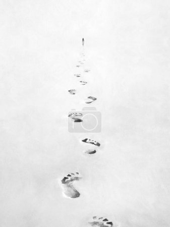 Téléchargez les photos : Illustration des pas en noir et blanc dans le sable, suivant le concept de personne - en image libre de droit