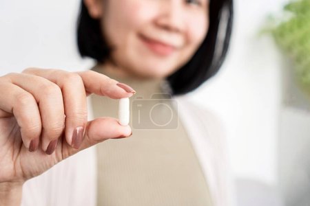 Téléchargez les photos : Femme asiatique tenant une pilule de supplément probiotique - en image libre de droit