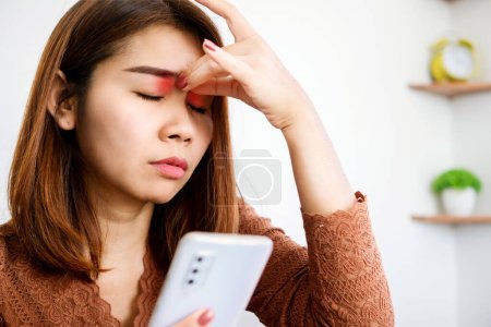 Foto de Mujer asiática experimenta dolor ocular causado por el tiempo de pantalla del teléfono inteligente, concepto de uso excesivo digital - Imagen libre de derechos