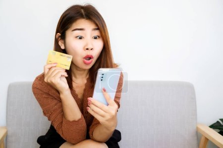 Foto de Emocionado shopaholic mujer asiática dispuesta a pagar por la venta de productos de mano con tarjeta de crédito y teléfono móvil - Imagen libre de derechos
