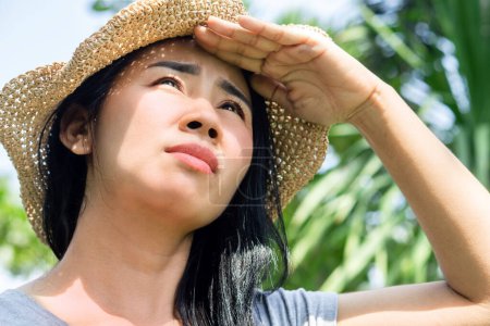 Mujer asiática con la cara quemada al sol de pie al aire libre bajo el sol de verano