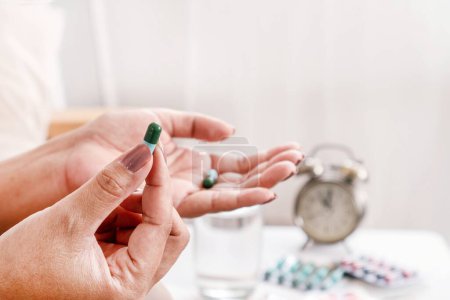Téléchargez les photos : La main d'une femme prend une pilule antibiotique dans le cadre d'un traitement antibiotique à long terme dans le traitement des infections bactériennes - en image libre de droit