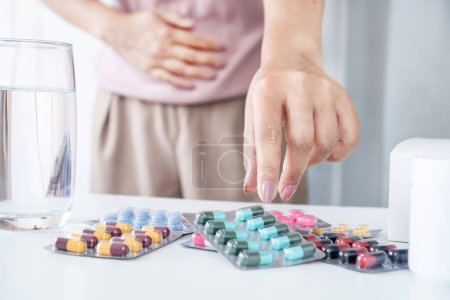 Foto de Primer plano de la mano de la mujer tomando una píldora antibiótica para tratar el dolor de estómago, infección de Dahlia - Imagen libre de derechos