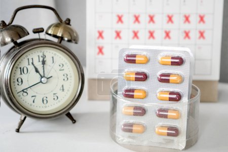 Photo for Long term schedule medication with antibiotics pills , calendar and alarm clock on desk - Royalty Free Image
