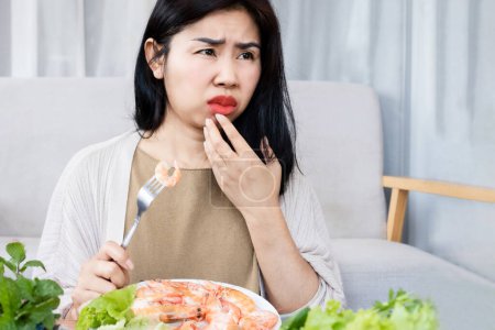 Photo for Asian women have an allergic reaction to shrimp, with swelling, and itching of the lips after eating seafood - Royalty Free Image
