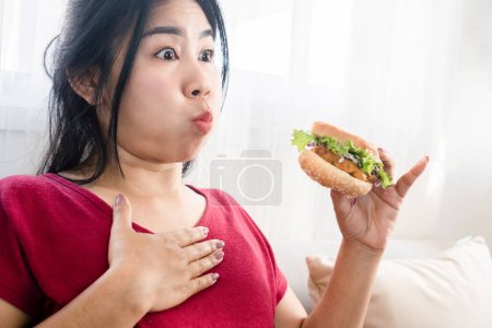 Téléchargez les photos : Asiatique femme accident chocking sur la nourriture et ne peut pas respirer tout en mangeant un hamburger qui coincé dans la gorge - en image libre de droit