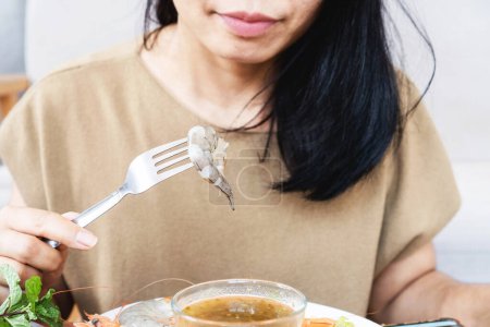 Téléchargez les photos : Femme asiatique mange des crevettes crues, fruits de mer non cuits pourraient tomber malade de l'intoxication alimentaire, concept de mauvaise alimentation - en image libre de droit
