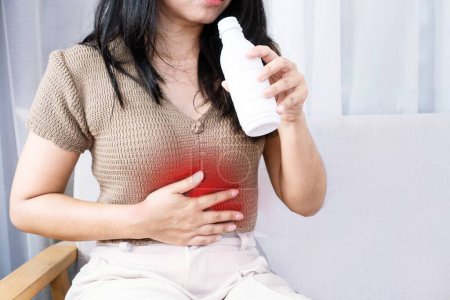 Foto de Mujer asiática que toma gel antiácido para tratar su acidez estomacal de gerd y dolor de estómago - Imagen libre de derechos
