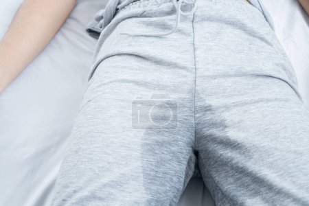 Photo for Closeup woman with wet pants because of Stress urinary incontinence can't control her pee while sleeping in bed - Royalty Free Image