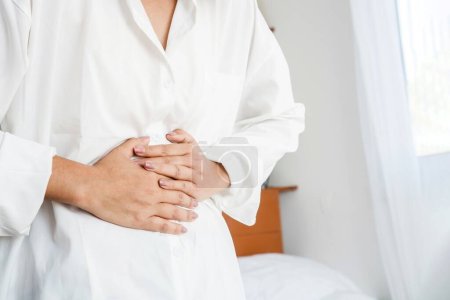 mujer que tiene con el sistema digestivo mano sosteniendo dolor de estómago