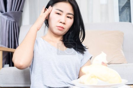 Photo for Asian woman having a problem with headache and dizziness after eating too much durian hand holding her head - Royalty Free Image