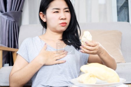 Asiatin hat ein Problem mit Sodbrennen, nachdem sie zu viel Durian Hand gegessen hat, die ihre Brustschmerzen hält