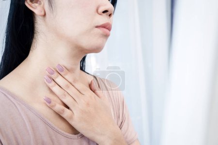 Téléchargez les photos : Femme asiatique ayant mal à la gorge, main toucher le cou sentir la douleur de l'inflammation - en image libre de droit