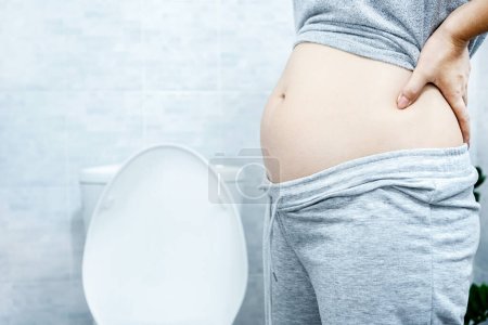 mujer con abdomen grande en el inodoro tiene problemas con el estreñimiento crónico, el síndrome del intestino perezoso y el concepto del sistema digestivo