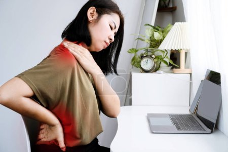 Mujer asiática que sufre de cuello, hombro y dolor en la parte inferior de la espalda debido al síndrome de oficina de trabajo prolongado por computadora