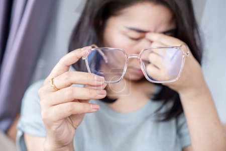 Mujer asiática que sufre de ojos cansados, visión borrosa, visión doble y dolor de cabeza, gafas de sujeción