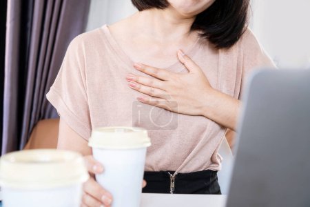 Photo for Asian woman having problems with heart palpitations or heart beating too fast after drinking coffee and too much caffeine - Royalty Free Image