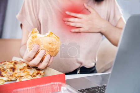 mujer que sufre de reflujo ácido, acidez estomacal después de comer comida chatarra, pizza y hamburguesa