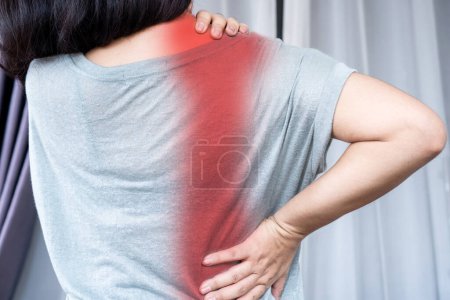 Frau leidet unter Schmerzen im Nacken und Schulterblatt, die sich aufgrund einer Muskelzerrung auf den unteren Rücken ausbreiten