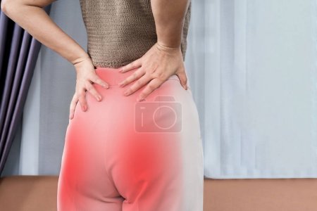Frau leidet unter Schmerzen im unteren Rücken und Gesäß, die sich auf das untere Bein ausbreiten, Ischiasschmerzkonzept 