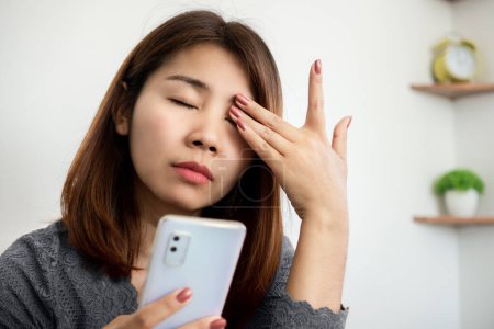Photo for Asian woman suffering from eye pain from phone screen time cause of blue light - Royalty Free Image