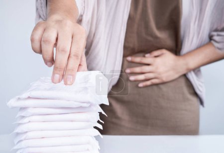 femme souffrant de crampes menstruelles pendant ses règles ressentant de la douleur dans le bas de l'abdomen main tenant un tampon hygiénique