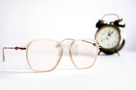 time to change , replace glasses prescription concept with closeup eyeglasses and blur background of alarm clock 