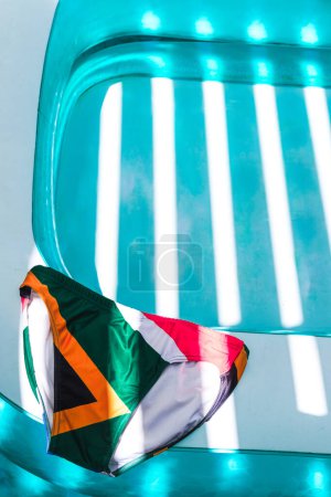 a pair of colorful swimming trunks laid by the side of a refreshing turquoise paddling pool on a bright sunny day