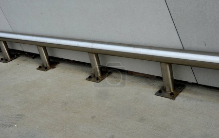 Photo for Around the facade and columns of the underground garage is a metal bumper made of stainless steel pipes anchored to the ground with screws. frame tube attached to the floor with four screws - Royalty Free Image