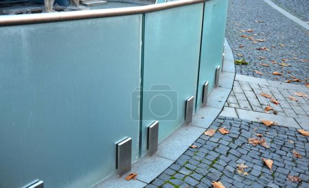 Geländer eines Luxushauses, bestehend aus Glaspaneelen, die mit grauen Edelstahlverkleidungen aus Metall befestigt sind. Die milchige Milchglasbarriere vermittelt einen luftigen Eindruck. Deckel aus poliertem Metall