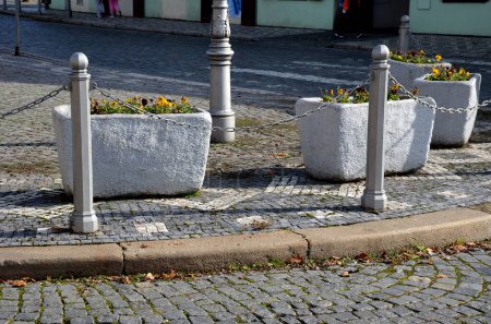 ornamental flower pots on village center trough concrete flower pots with beautiful decorations of violets and daffodils. Easter is approaching so it is necessary to decorate entrance of home, parking-stock-photo