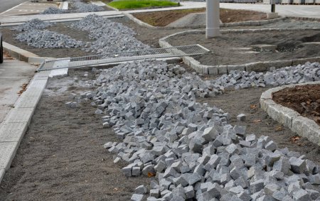 Photo for Pavers made of stone cubes who can create beautiful mosaics. piles prepared in fine gravel for laying between curbs. the mayor ordered new sidewalks from the construction company - Royalty Free Image